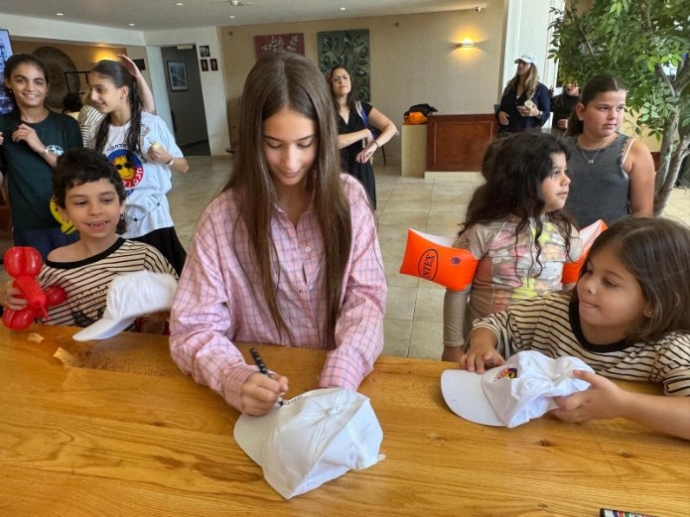 אביגיל ויסמן חותמת לילדים במהלך הביקור בנופש. צילום: האגודה למלחמה בסרטן