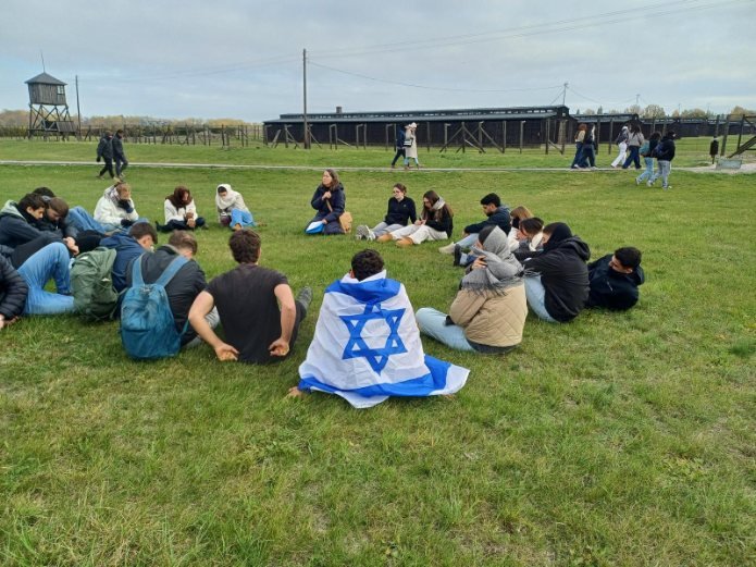 תלמידי שער הנגב עטופים בדגלי ישראל במפגש קבוצתי בשטח מחנה בפולין. צילום: דור וייצמן